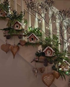 christmas decorations are hanging on the banisters in this staircase case, which is decorated with birdhouses and pine cones