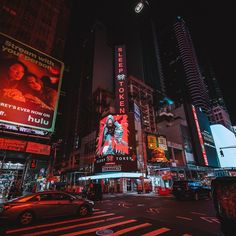 a city street filled with lots of traffic and tall buildings lit up at night time