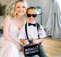 a young boy and woman sitting on top of a bed holding a ring security box