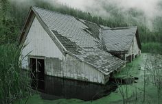 an old barn in the middle of some water