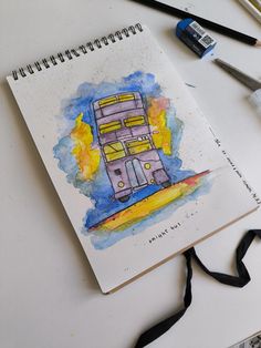 a drawing of a double decker bus on top of a white table next to paintbrushes