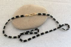 a black and gold beaded necklace on a rock