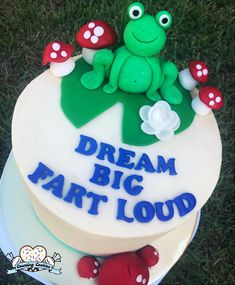 there is a cake that says dream big part loud on the top with a frog sitting on it