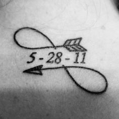 the back of a woman's neck with an arrow and date tattoo on it