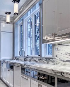 a kitchen with marble counter tops and stainless steel appliances in the center, along with large windows