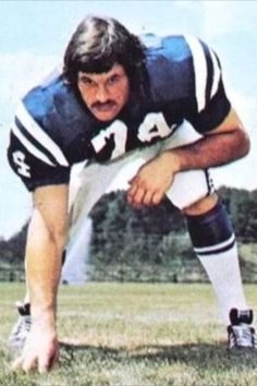 an old photo of a football player kneeling down in the grass with his foot on the ground