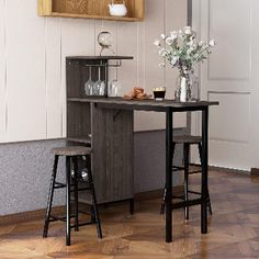 two stools sit in front of a table with flowers on it and shelves above