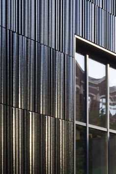 the side of an office building with large windows and metal slats on it's facade