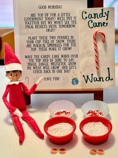 an elf is sitting next to two bowls of candy canes and a sign that says candy canes