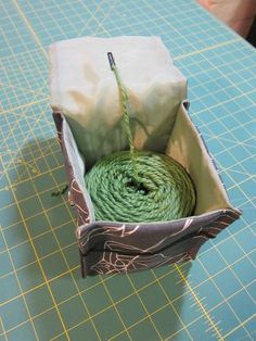 a roll of green rope in a box on top of a cutting mat with scissors