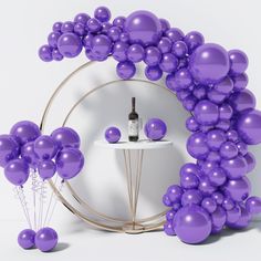 a wine bottle is sitting on a table surrounded by purple balloons that are floating in the air