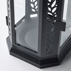 a black and white photo of a candle holder with cut out leaves on it's sides