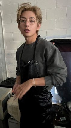 a young man wearing glasses and an apron