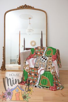 a baseball themed blanket is on the floor in front of a mirror