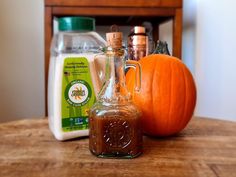 a bottle of liquid sitting on top of a wooden table next to a pumpkin and other items