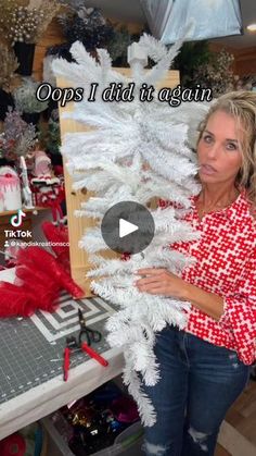 a woman standing in front of a white christmas tree with red and white decorations on it