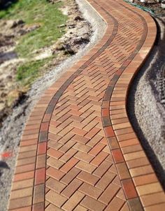 a red brick walkway with green grass and trees in the background