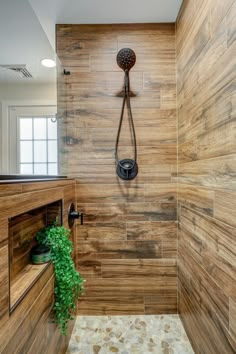 a shower with wooden walls and tile flooring next to a potted green plant