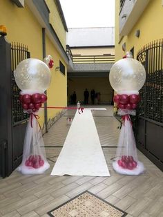 two large balloons are tied to poles in the middle of a hallway with white and red decorations