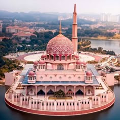 an aerial view of a pink building in the middle of a body of water with buildings around it