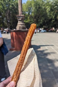 a person holding up a large piece of food in their hand on the sidewalk near a statue