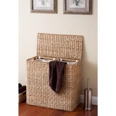 a large woven storage basket with two pictures on the wall behind it and a brown towel hanging in front of it