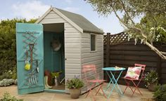 a small garden shed with two chairs and a table