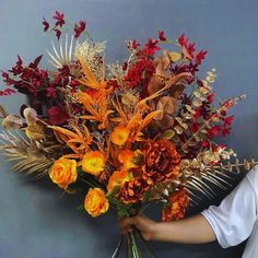 a person holding a bouquet of flowers against a wall