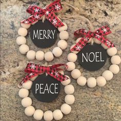 three christmas ornaments with words on them and bows around the wreaths that say merry, noel, noel