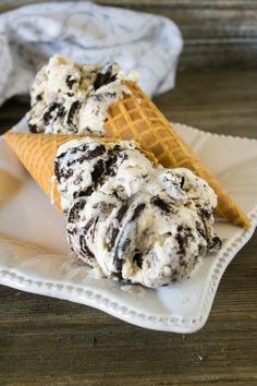 two scoops of ice cream sitting on top of a white plate with waffle cones