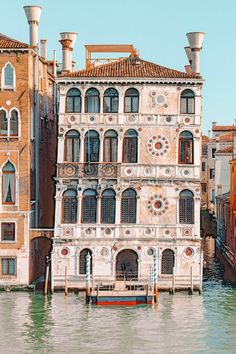 an old building in the middle of water next to buildings with windows and balconies