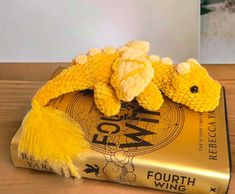 a yellow stuffed animal laying on top of a book