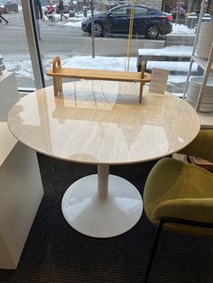 a white table and two chairs in front of a window with snow on the ground