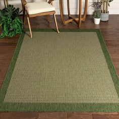 a green area rug in the middle of a room with two chairs and a potted plant