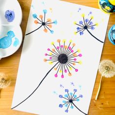 a dandelion painted on a piece of paper next to some plates and spoons