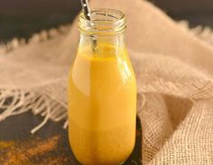 a glass jar filled with yellow liquid sitting on top of a white cloth covered table