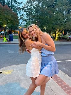 two women hugging each other on the sidewalk