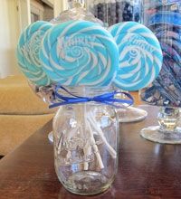 three lollipops in a glass jar on a table with other items behind it