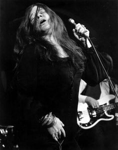 an old black and white photo of a woman singing into a microphone while holding a guitar