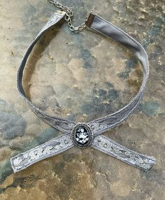 This is my version of the family crest choker as seen worn by the amber eyed vampire family. The crest is set behind glass into an antiqued silver bezel. Its attached to a 14 inch choker with an adjustable clasp. The choker is made of cotton and lace, carefully stitched together to give it a unique antique shabby chic feel. This makes an excellent gift for a loved one or yourself. Silver Choker For Halloween Gift, Adjustable Silver Halloween Choker, Adjustable Silver Choker For Halloween, Silver Vampire Choker For Halloween, Silver Vampire Style Choker As Gift, Gothic Silver Choker For Gift, Gothic Silver Choker As A Gift, Silver Gothic Choker For Gift, Silver Gothic Choker As A Gift