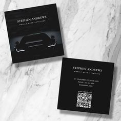 two black business cards sitting on top of a white marble counter