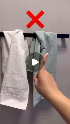 a person is pointing at towels hanging on a rack with two red crosses over them