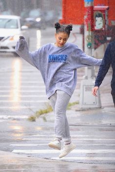 two people walking down the street in the rain with an umbrella over their head and one person wearing a kansas sweatshirt