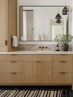 a bathroom with wooden cabinets and a large mirror above the sink, along with a rug on the floor