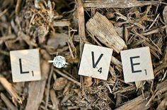 the word love spelled with scrabbles on wood chips in front of a diamond ring