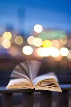 an open book sitting on top of a wooden table next to a cityscape