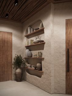 a room with some shelves and vases on the wall next to each other in it