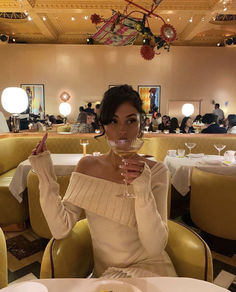 a woman sitting at a table with a wine glass in her hand and food on the plate