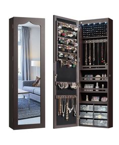 an open mirrored closet with jewelry on the door and mirror above it, in front of a couch