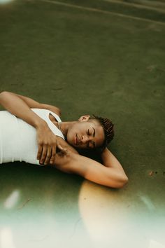 a woman laying on the ground with her arm around her neck and head resting on her chest